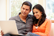 Hispanic couple at home with laptop Man and Woman looking at a document