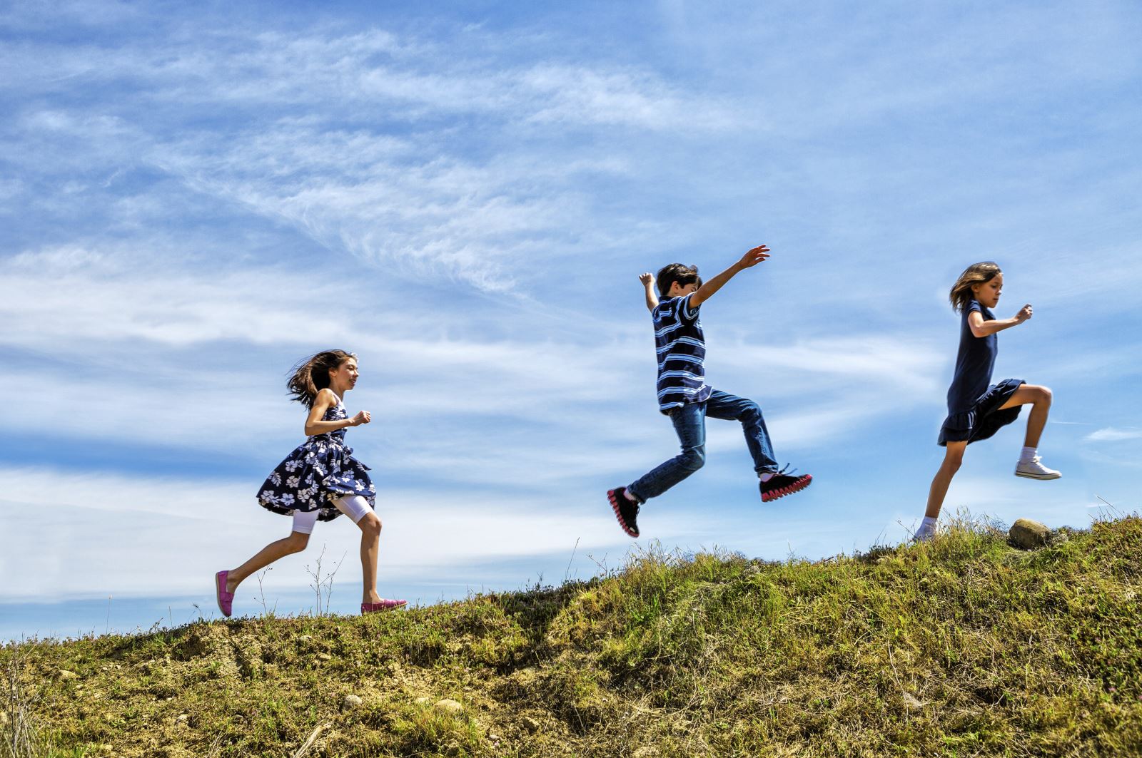 Three children running on grass
